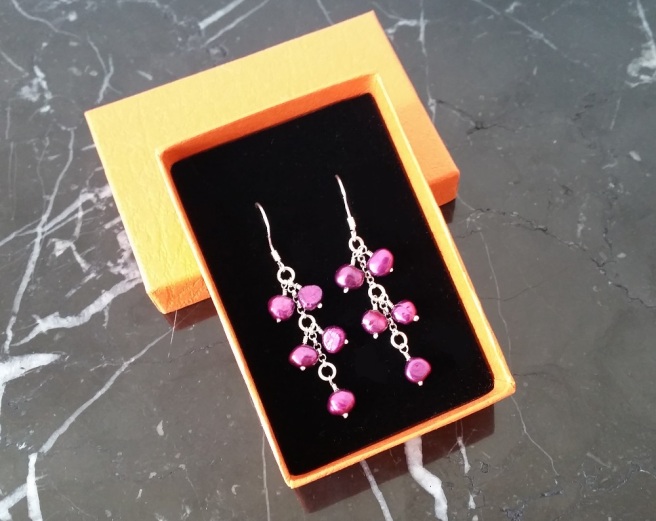 Purple pearl earrings in a bright orange box