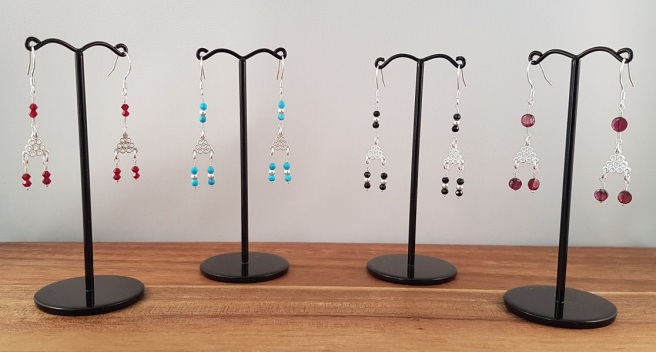 Four pairs of triangle earrings on black stands